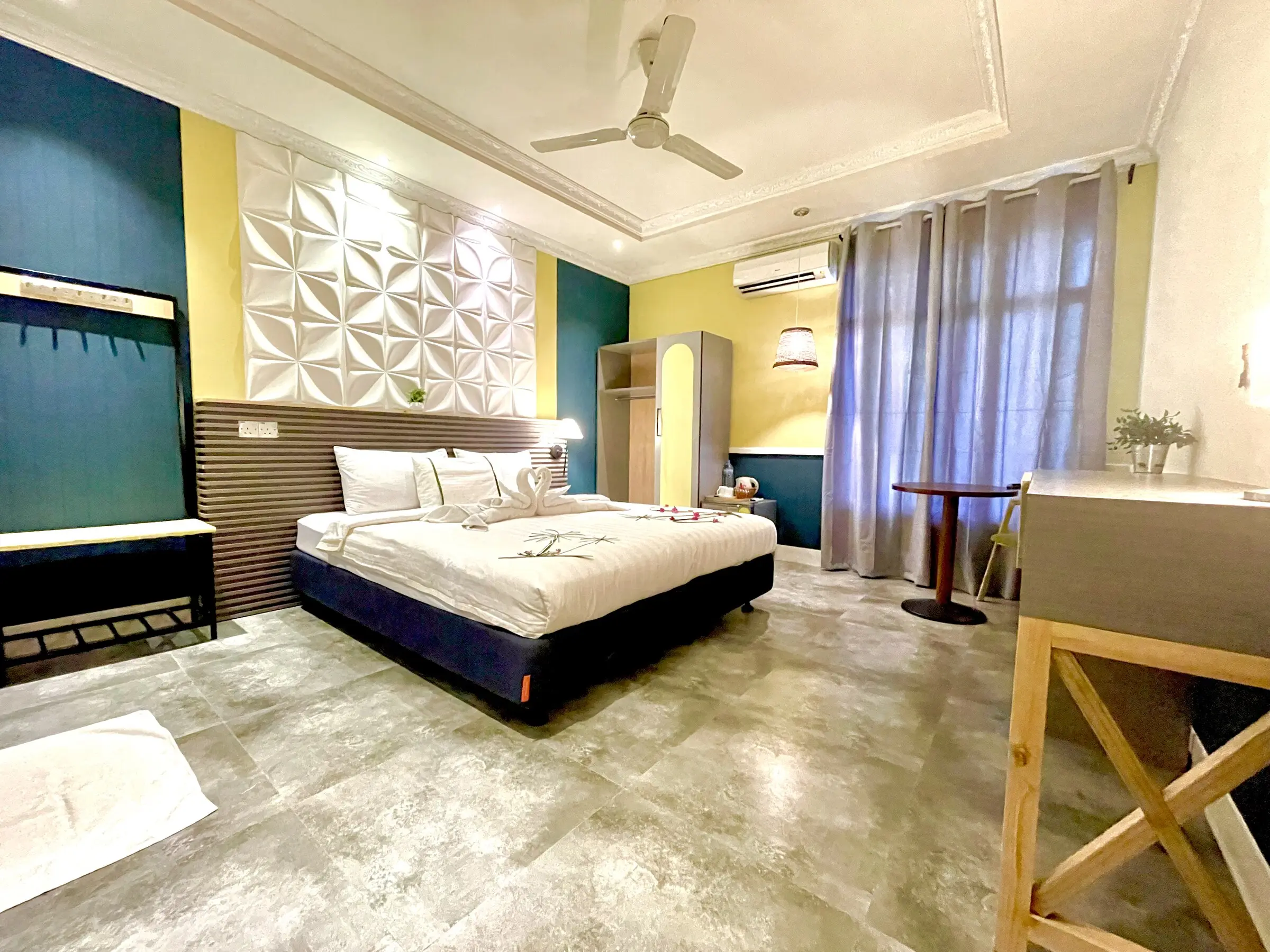 Bright room with a double bed and yellow feature wall at Koimala Maamigili