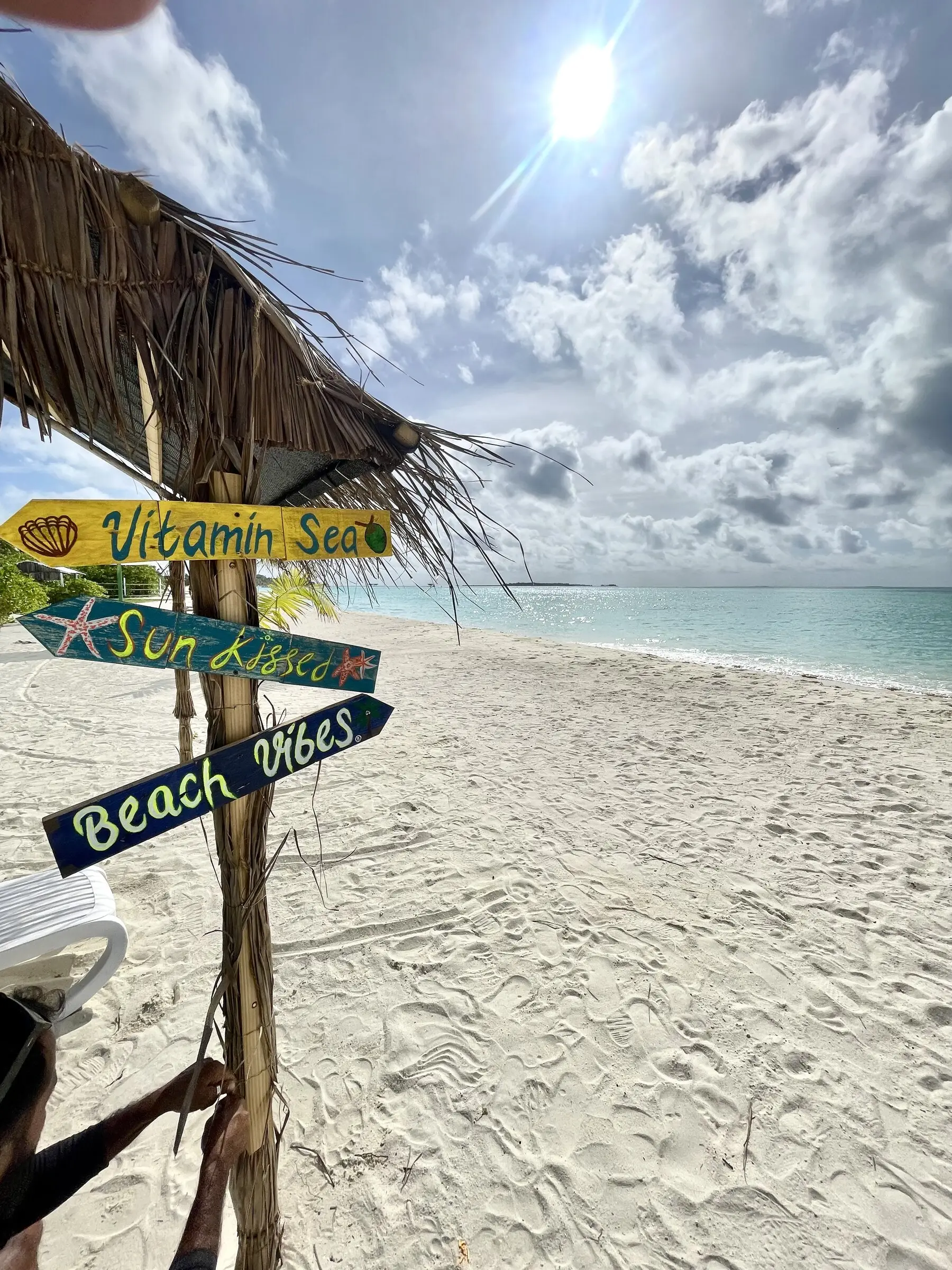 Bikini beach signpost among palms on Maamigili's white sand