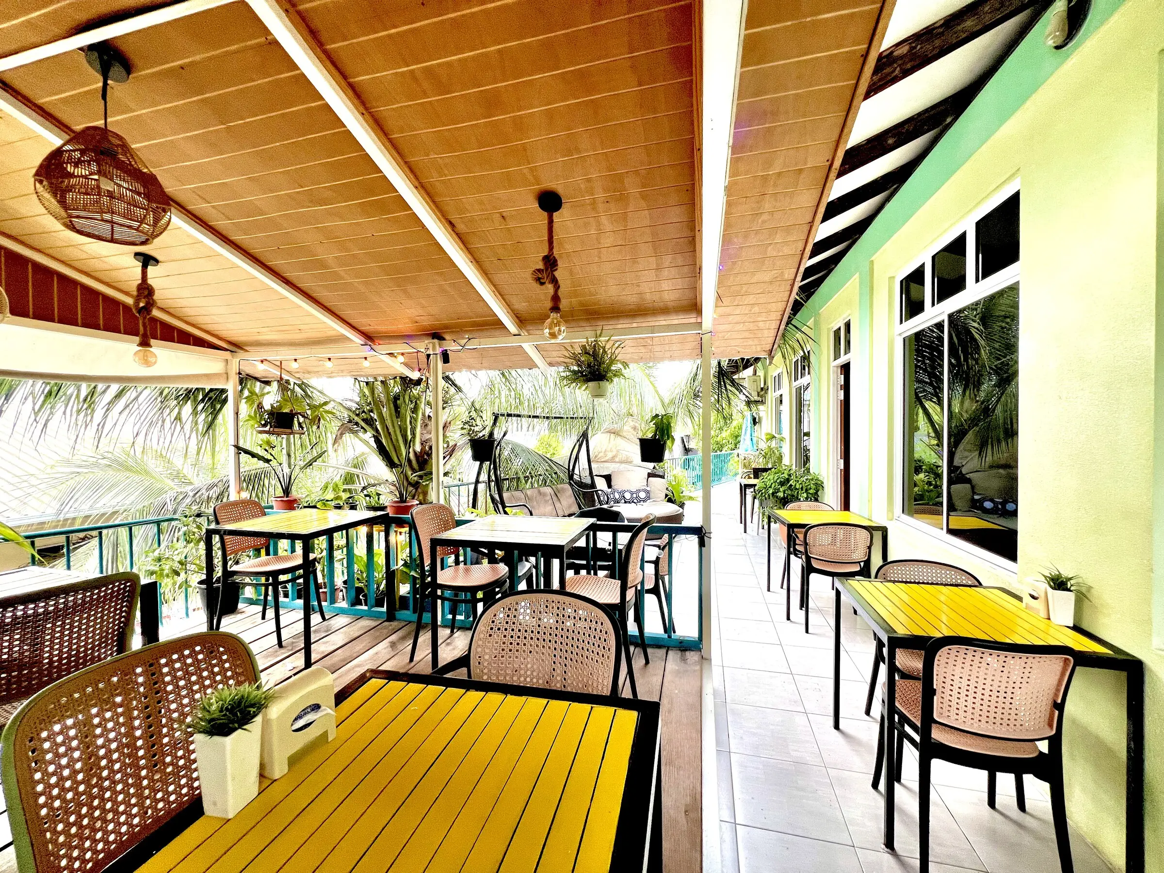 Covered dining terrace with a timber ceiling and greenery at Koimala Maamigili