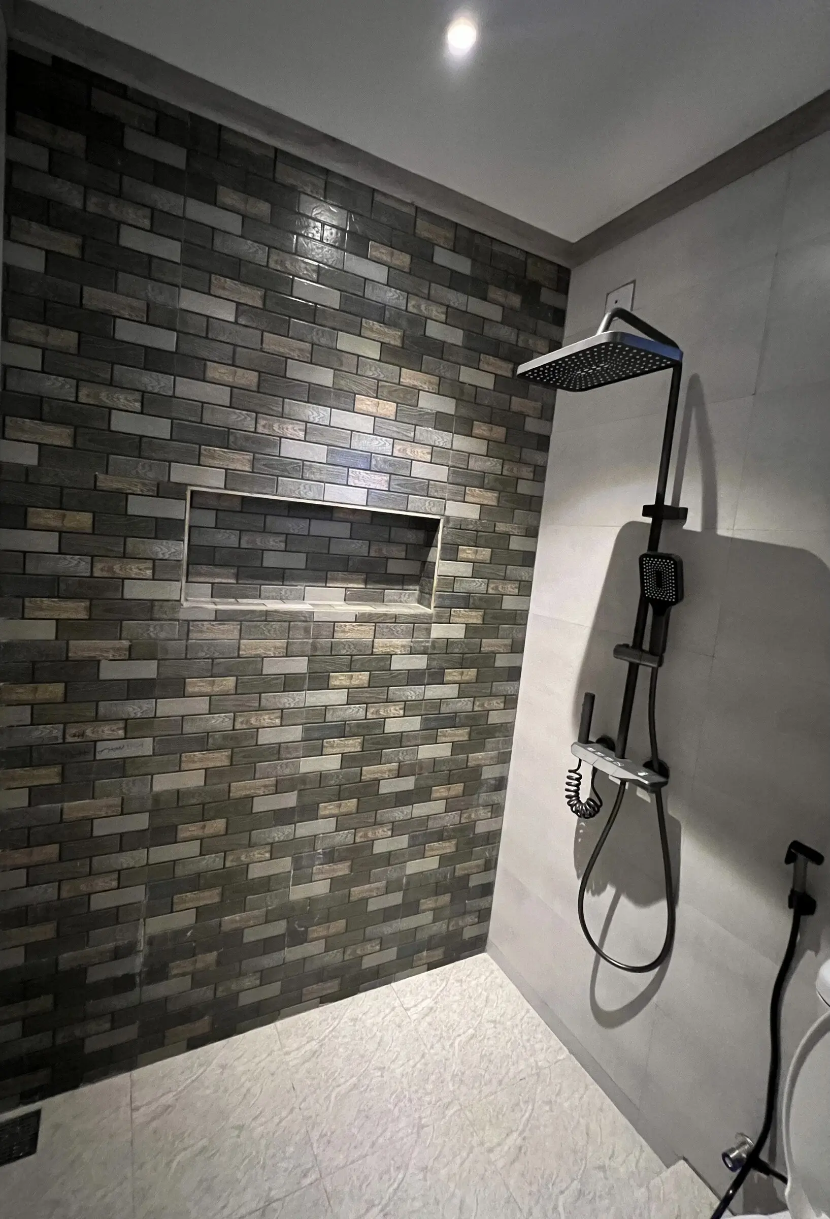 Walk-in shower with dark stone tiling at Koimala Maamigili