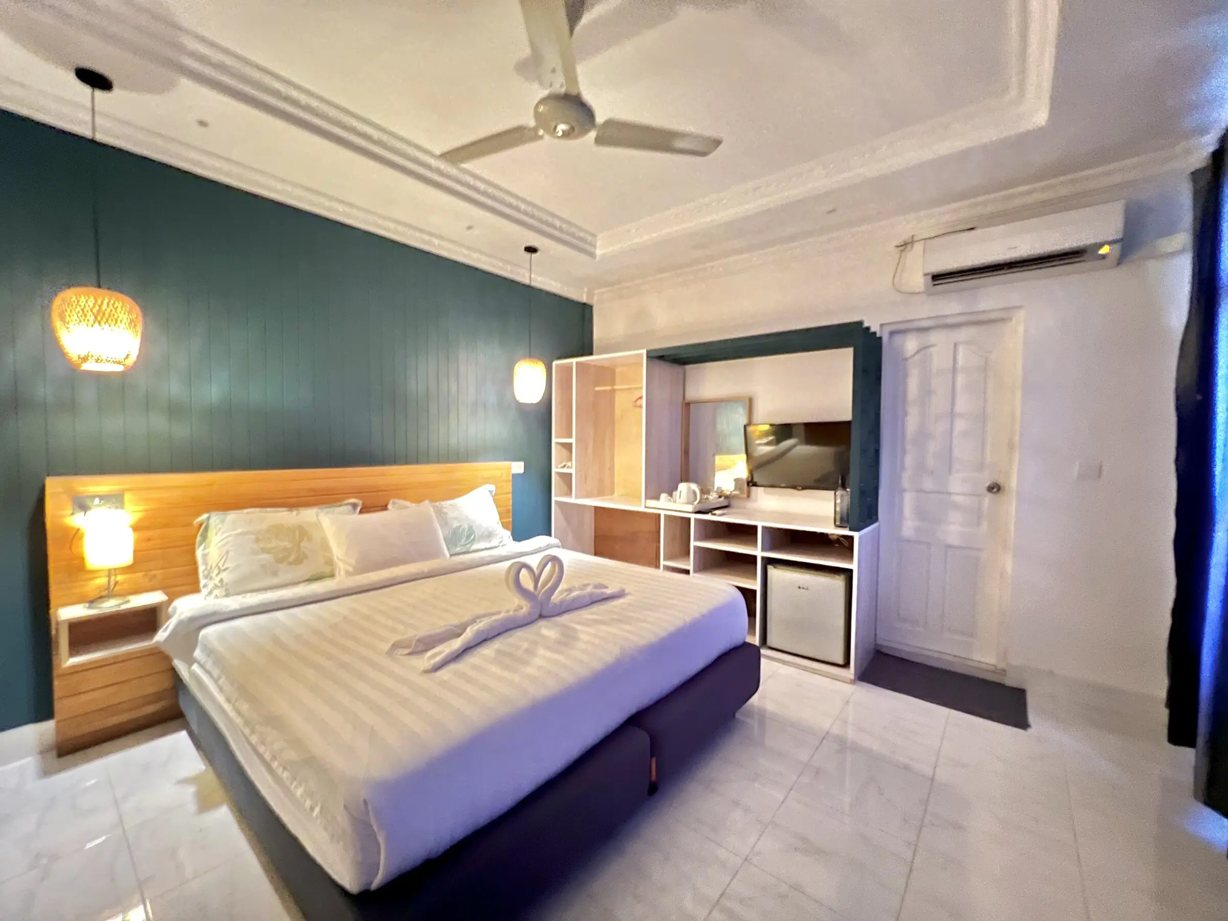 Double bed with warm lighting and a dark feature wall at Koimala Maamigili