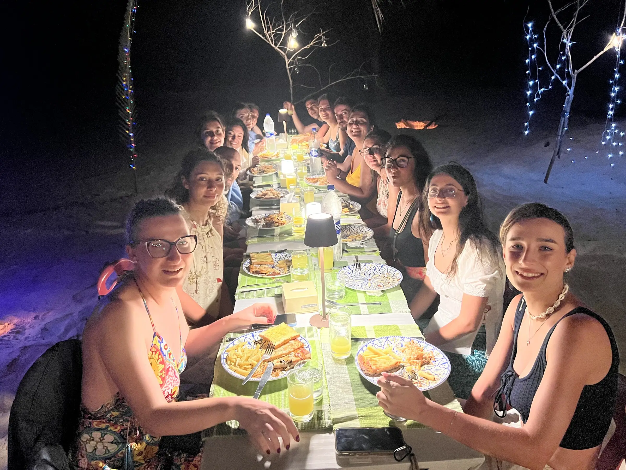 Group celebration dinner under festoon lights at Koimala Maamigili